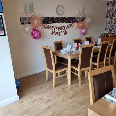 a table with balloons and a sign that says happy birthday sweet at Trevarrian Lodge in Newquay