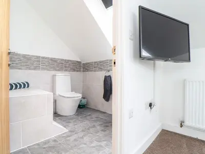 a bathroom with a toilet and a tv on the wall at Atlantic Reach in Marazion