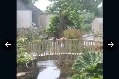 a woman standing on a fence looking at a pond at Stunning Holiday home with amazing surroundings! in Budock Water