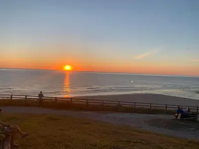 people sitting on benches watching the sunset on the beach at Beautiful Cornish Getaway, Static Caravan - Newperran Holiday Resort in Cubert