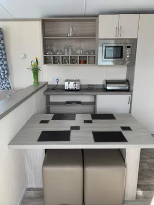 a kitchen with a table and a microwave at Beautiful Cornish Getaway, Static Caravan - Newperran Holiday Resort in Cubert