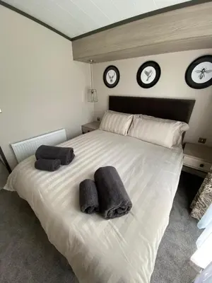 a bedroom with a large white bed with three clocks on the wall at Riverwood Lodge in Porth
