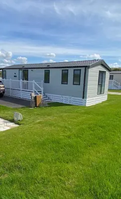 a mobile home in a yard with green grass at Riverwood Lodge in Porth