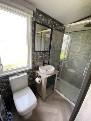 a bathroom with a toilet and a sink and a shower at Riverwood Lodge in Porth