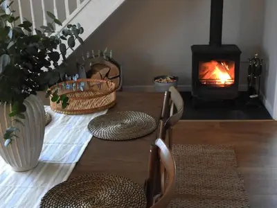 a living room with a fireplace and a wooden table with mats at Cargibbitt Annexe in Liskeard