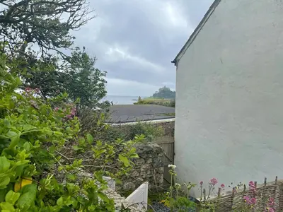a white house with a garden next to a building at Cosy Cottage Central Marazion with Parking in Marazion