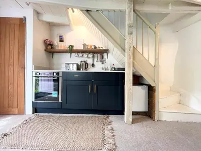 a kitchen with blue cabinets and a staircase at Cosy Cottage Central Marazion with Parking in Marazion