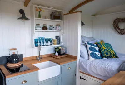 a kitchen with a sink and a bed in a room at Luxury Shepherd's Hut on Meadow with Outdoor Bath in Mid Cornwall in Truro