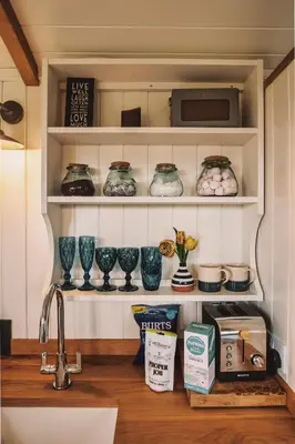 a kitchen counter with bowls and vases on shelves at Luxury Shepherd's Hut on Meadow with Outdoor Bath in Mid Cornwall in Truro