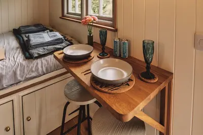 a small kitchen with a wooden table with two bowls on it at Luxury Shepherd's Hut on Meadow with Outdoor Bath in Mid Cornwall in Truro
