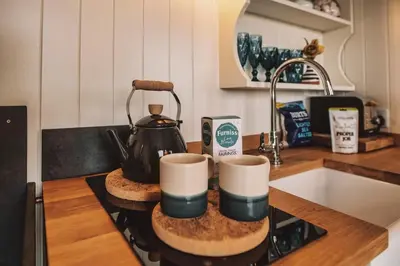 a tea kettle on top of a stove in a kitchen at Luxury Shepherd's Hut on Meadow with Outdoor Bath in Mid Cornwall in Truro