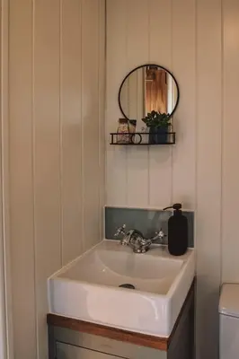 a white sink in a bathroom with a mirror at Luxury Shepherd's Hut on Meadow with Outdoor Bath in Mid Cornwall in Truro