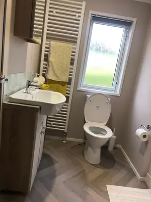 a bathroom with a toilet and a sink and a window at Mawgan Stays Mawgan Porth in Mawgan Porth