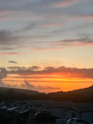 a sunset over a parking lot with cars parked at Mawgan Stays Mawgan Porth in Mawgan Porth