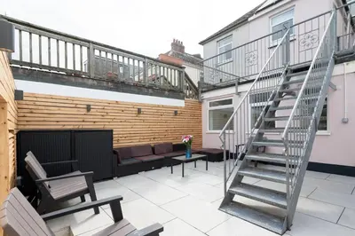 a patio with a couch and a spiral stair case at TRIG-Private Studio, Courtyard, Walk to Fistral in Newquay