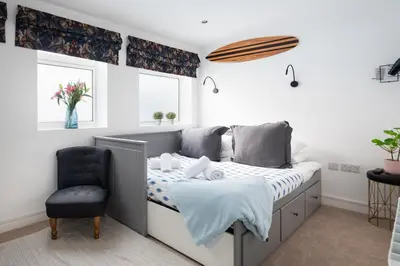 a bedroom with a bed and a blue chair at TRIG-Private Studio, Courtyard, Walk to Fistral in Newquay