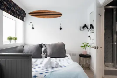 a bedroom with a bed with a blue and white blanket at TRIG-Private Studio, Courtyard, Walk to Fistral in Newquay