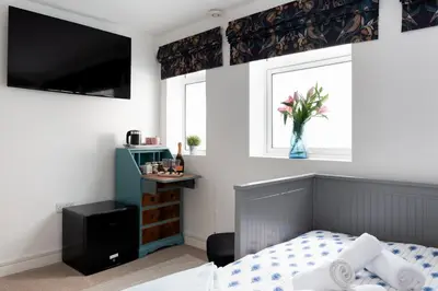 a bedroom with a bed and a vase of flowers in a window at TRIG-Private Studio, Courtyard, Walk to Fistral in Newquay
