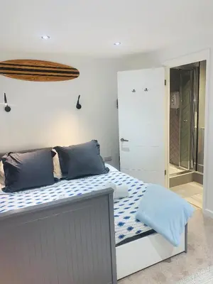 a bedroom with a large bed with blue pillows at TRIG-Private Studio, Courtyard, Walk to Fistral in Newquay
