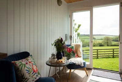 a living room with a table and chairs and a sliding glass door at Safari Cornwall in Bodmin
