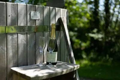a bottle of wine and two glasses sitting on a chair at Safari Cornwall in Bodmin