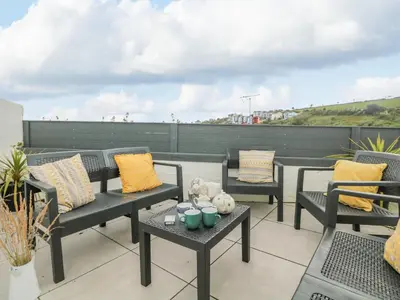 a patio with chairs and tables on a roof at Chy An Mor in Mevagissey