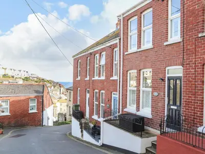 a red brick house with a balcony in a street at Chy An Mor in Mevagissey
