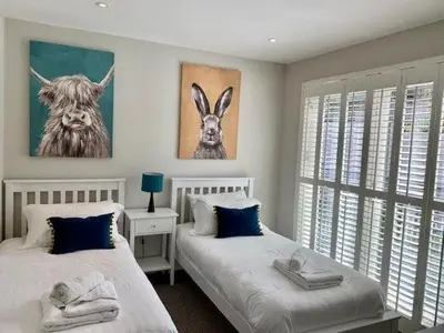 two beds in a bedroom with two rabbits on the wall at House 11 in Looe