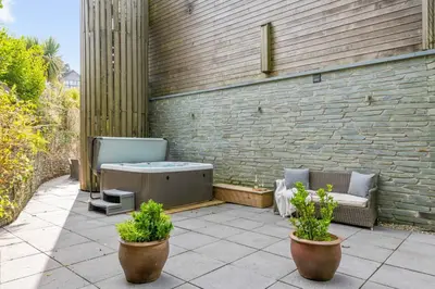a patio with a hot tub and two potted plants at House 1 in Looe