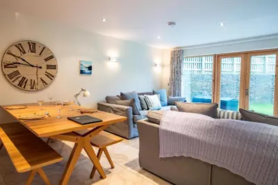 a living room with a table and a clock on the wall at House 1 in Looe