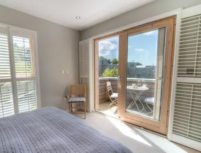 a bedroom with a bed and a view of a balcony at House 1 in Looe