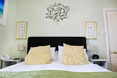 a bedroom with a bed with white sheets and yellow pillows at Blue Sky Bed and Breakfast in St Ives
