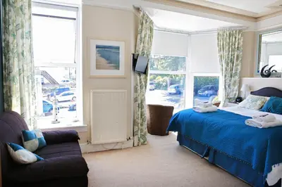 a bedroom with a bed and a couch and windows at Blue Sky Bed and Breakfast in St Ives