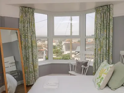 a bedroom with a bed and a large window at Rock Lobster in Helston