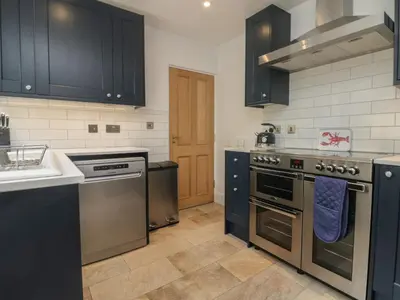 a kitchen with stainless steel appliances and black cabinets at Rock Lobster in Helston