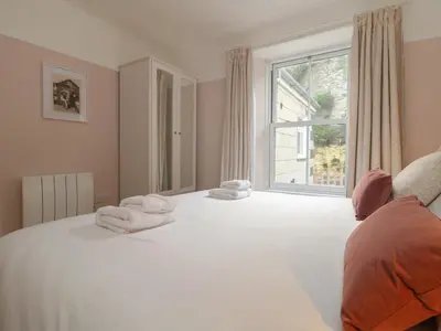 a bedroom with a large white bed with towels on it at Rock Lobster in Helston