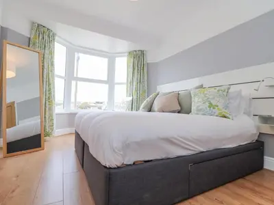 a bedroom with a large bed with a large window at Rock Lobster in Helston
