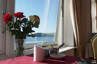 a vase of flowers sitting on a table with a window at Membly Hall Hotel in Falmouth
