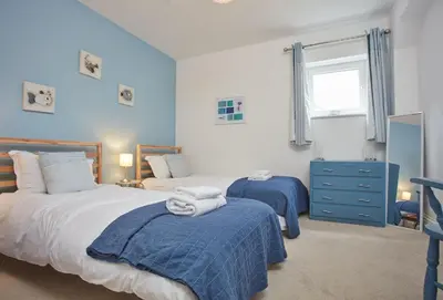 a bedroom with two beds with blue walls and a window at Anneth Lowen in Polzeath