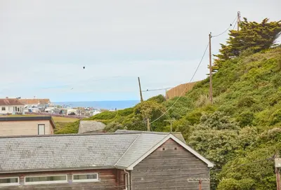 a house on a hill with the ocean in the background at Anneth Lowen in Polzeath