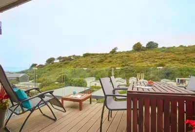a deck with chairs and a table and a pool at Anneth Lowen in Polzeath