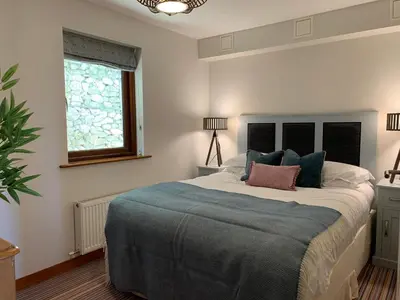 a bedroom with a large bed with a blue blanket at White Lodge - Coast Hideaways in Mawgan Porth