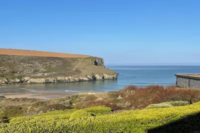 a view of a beach with a house and the ocean at White Lodge - Coast Hideaways in Mawgan Porth