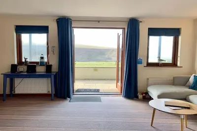 a living room with a couch and a large window at White Lodge - Coast Hideaways in Mawgan Porth