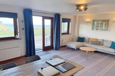 a living room with a couch and a table at White Lodge - Coast Hideaways in Mawgan Porth
