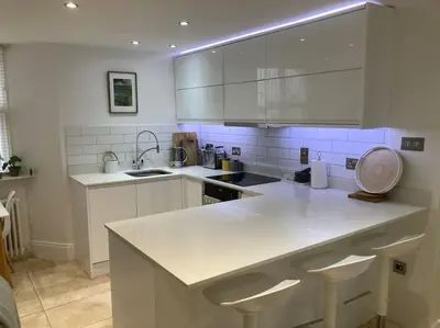 a kitchen with white cabinets and a white counter top at Acuba in Falmouth