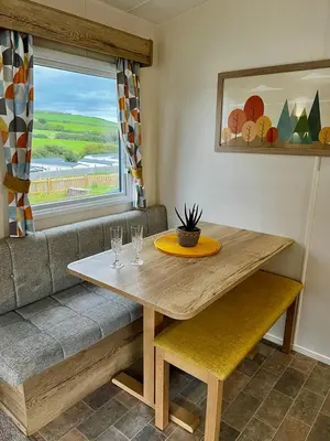 a wooden table with two glasses and a couch at Newquay Bay Resort - Summer Days 135 in Porth