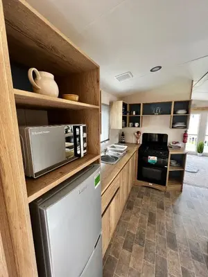 a kitchen with wooden cabinets and a stainless steel refrigerator at Newquay Bay Resort - Summer Days 135 in Porth