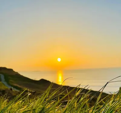 a sunset on the beach with the sun setting over the ocean at Newquay Bay Resort - Summer Days 135 in Porth