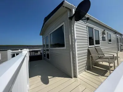 a mobile home with a deck with a chair at Newquay Bay Resort - Summer Days 135 in Porth